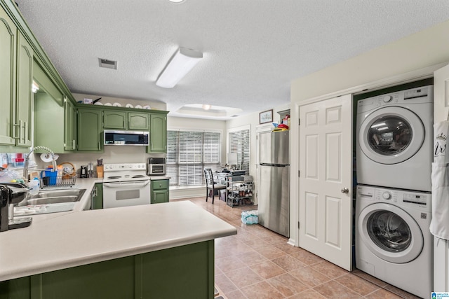 interior space with a textured ceiling, sink, light tile patterned floors, and stacked washing maching and dryer