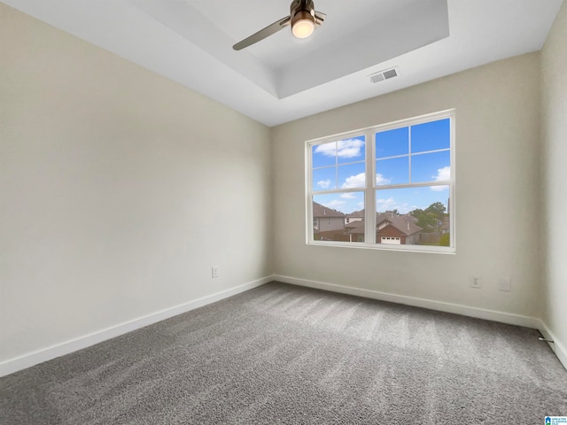 carpeted empty room with ceiling fan and a raised ceiling