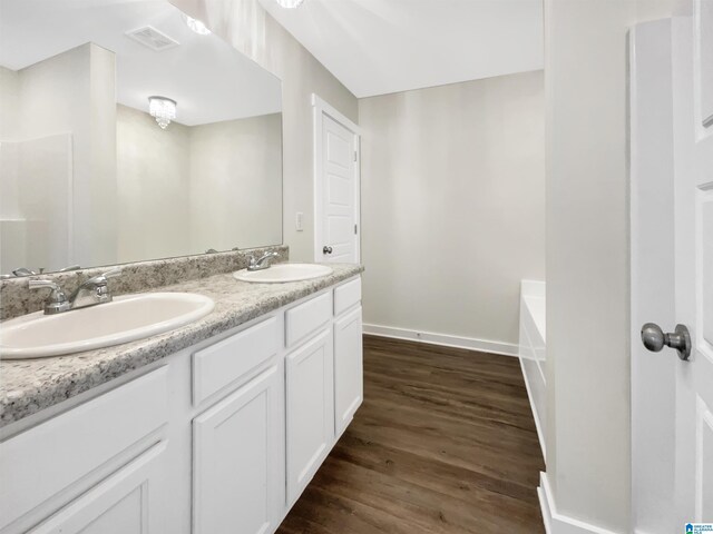 bathroom featuring vanity, a bath, and wood-type flooring