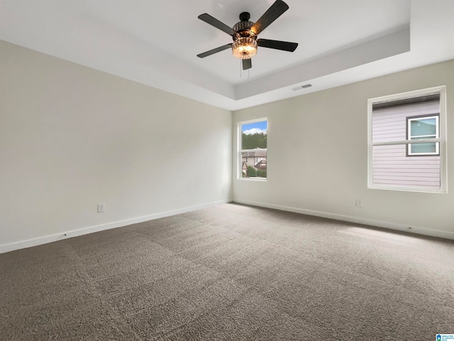 carpeted empty room with ceiling fan and a tray ceiling