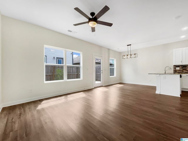 unfurnished living room featuring dark wood-type flooring, ceiling fan, and sink