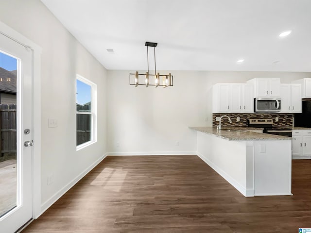 kitchen with appliances with stainless steel finishes, light stone counters, a wealth of natural light, and kitchen peninsula