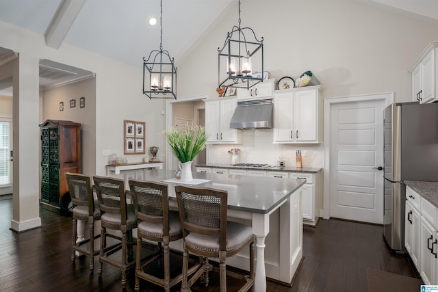 kitchen featuring appliances with stainless steel finishes, a kitchen island, an inviting chandelier, and dark wood-type flooring