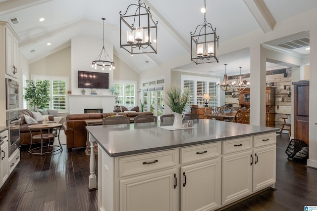 kitchen with plenty of natural light, dark wood-type flooring, hanging light fixtures, and a fireplace