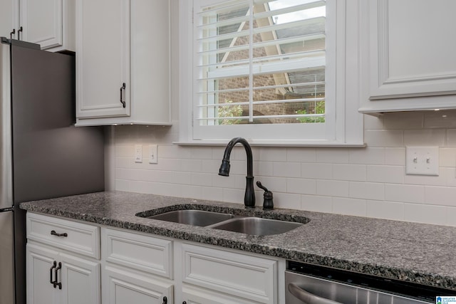 kitchen with stainless steel appliances, sink, white cabinetry, and dark stone counters