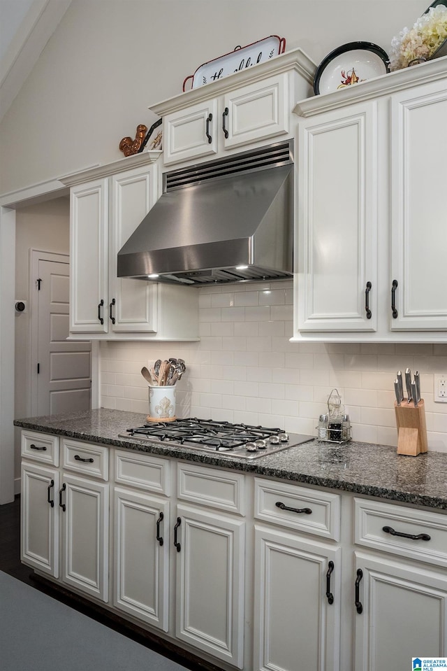 kitchen with dark stone countertops, stainless steel gas cooktop, exhaust hood, and tasteful backsplash