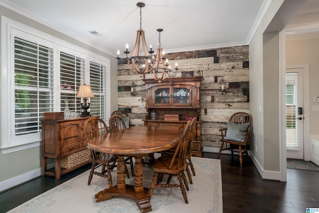 dining space with dark hardwood / wood-style flooring, an inviting chandelier, wood walls, and ornamental molding