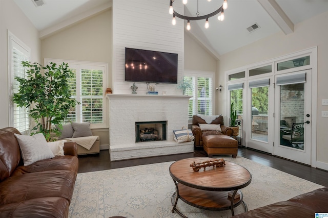 living room with a notable chandelier, a stone fireplace, dark wood-type flooring, high vaulted ceiling, and beam ceiling