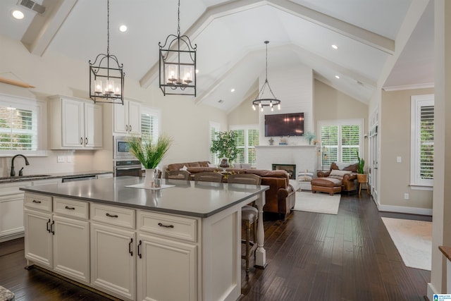 kitchen with a fireplace, appliances with stainless steel finishes, a notable chandelier, sink, and dark wood-type flooring