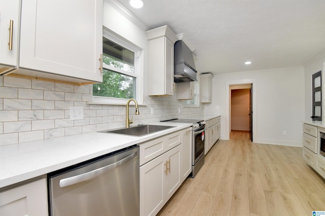 kitchen featuring white cabinets, custom exhaust hood, stainless steel appliances, light hardwood / wood-style floors, and sink