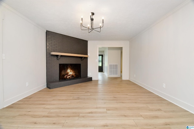 207 Friendship Cir, Clanton, AL 35045 - unfurnished living room with a brick fireplace, ornamental molding, a chandelier, visible vents, and light wood-style flooring