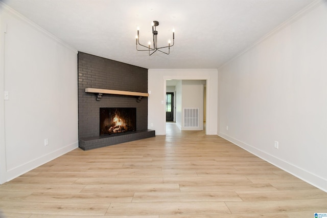 unfurnished living room featuring light wood-type flooring, ornamental molding, a brick fireplace, and a chandelier