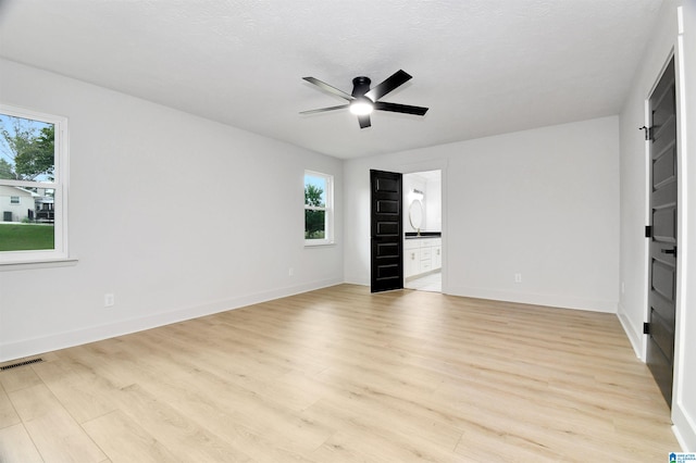 unfurnished bedroom with light hardwood / wood-style flooring, ensuite bath, ceiling fan, and multiple windows