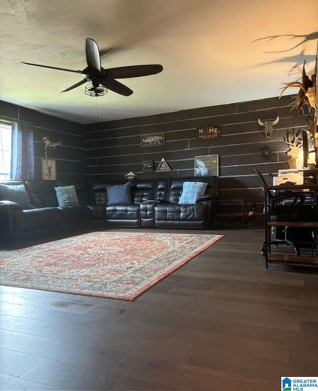 living room featuring hardwood / wood-style flooring, wood walls, and ceiling fan