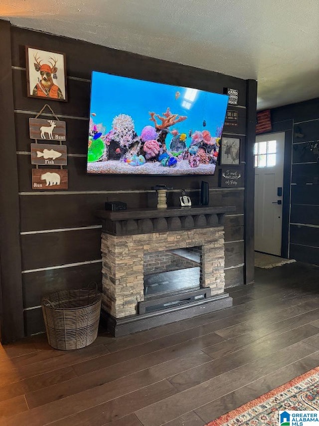 interior details featuring a textured ceiling, hardwood / wood-style floors, and a stone fireplace