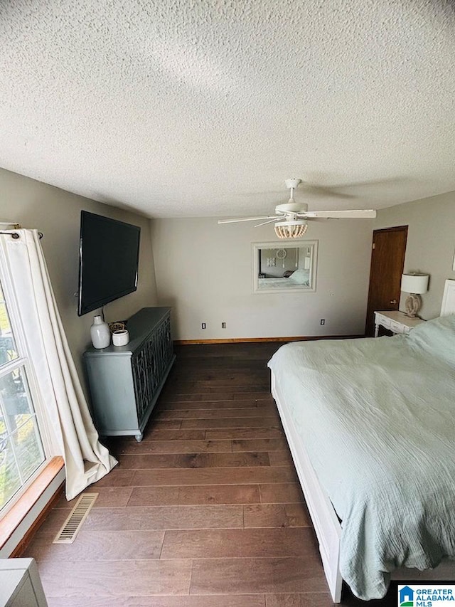 bedroom featuring ceiling fan, dark hardwood / wood-style flooring, and a textured ceiling