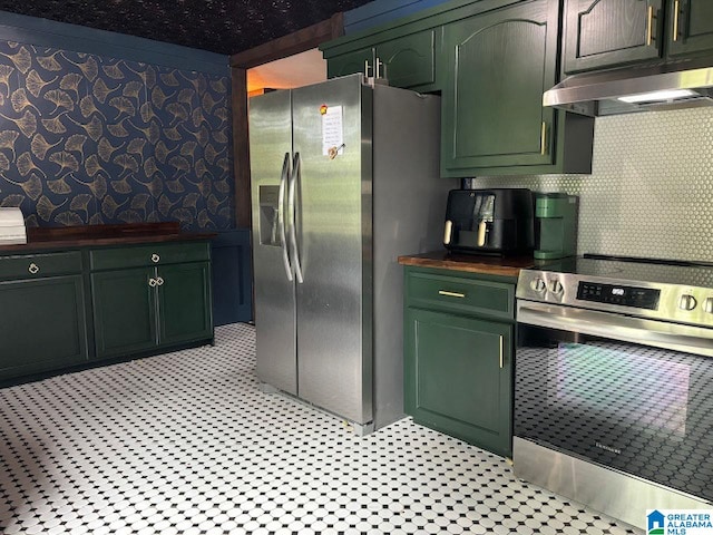 kitchen with appliances with stainless steel finishes, green cabinets, and butcher block counters