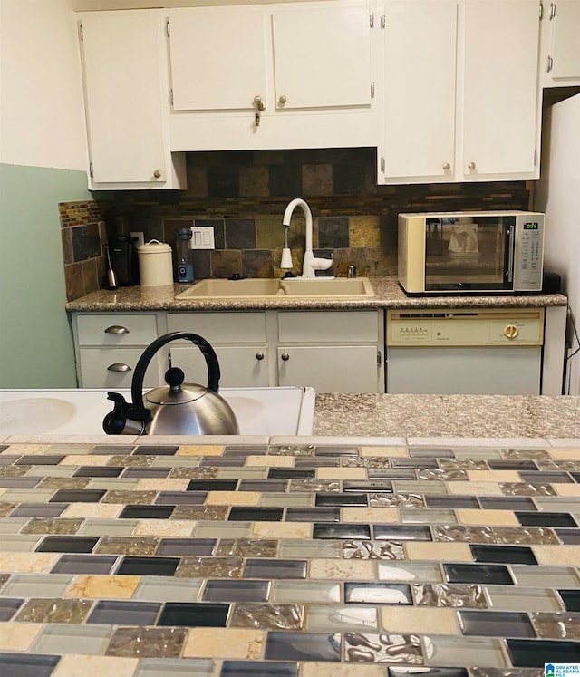 kitchen featuring white cabinets, white dishwasher, tasteful backsplash, and sink