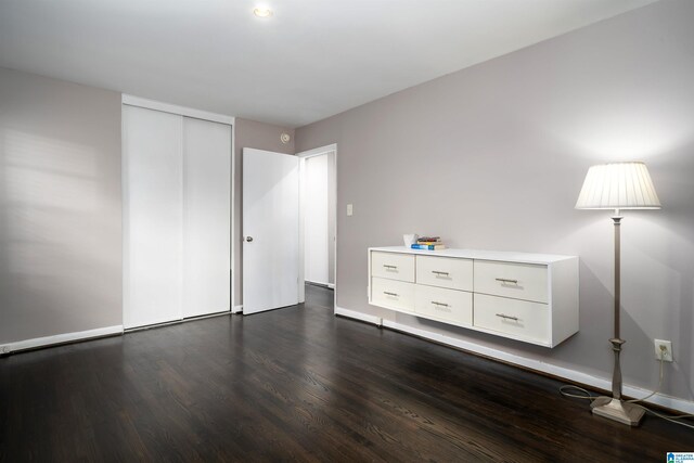 unfurnished bedroom with dark hardwood / wood-style floors and a closet