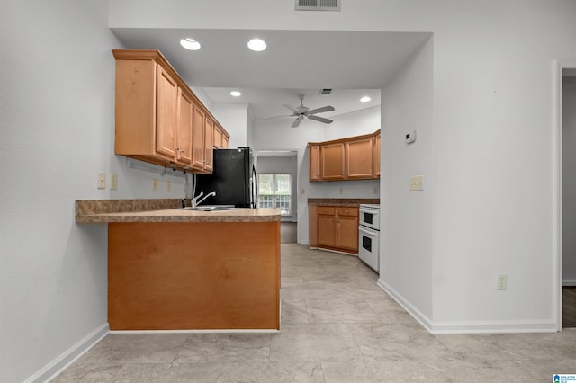 kitchen featuring white range oven, kitchen peninsula, sink, ceiling fan, and black fridge