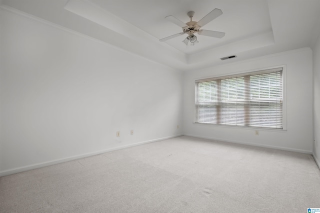 carpeted spare room with crown molding, a raised ceiling, and ceiling fan