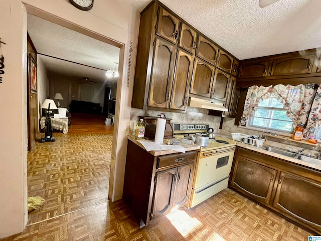 kitchen with a textured ceiling, light parquet floors, dark brown cabinetry, and white electric range oven