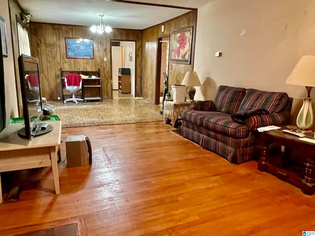 living room with wood walls, wood-type flooring, and a chandelier