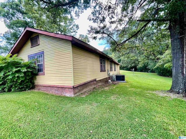 view of side of property featuring a yard and central AC