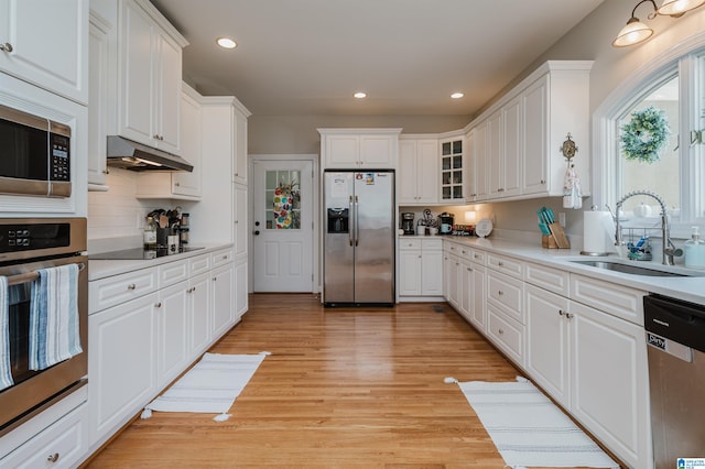 kitchen featuring light wood-type flooring, sink, decorative backsplash, appliances with stainless steel finishes, and white cabinets