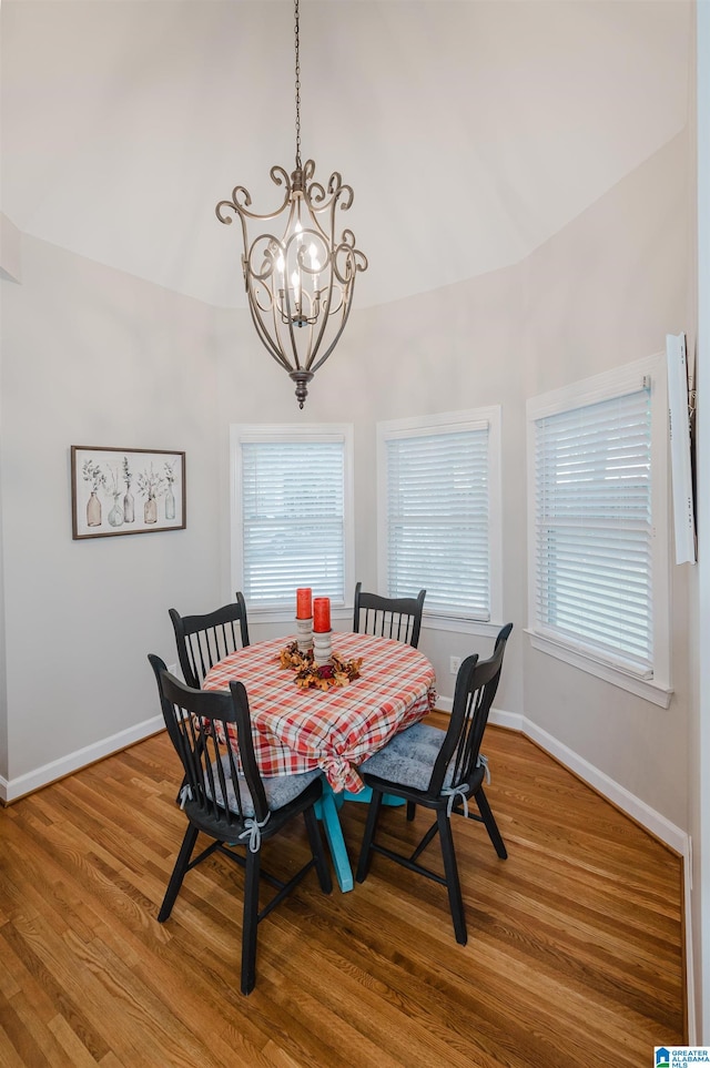 dining room featuring lofted ceiling, wood-type flooring, and an inviting chandelier