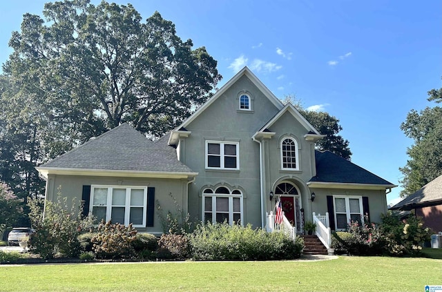 view of property featuring a front lawn and central AC