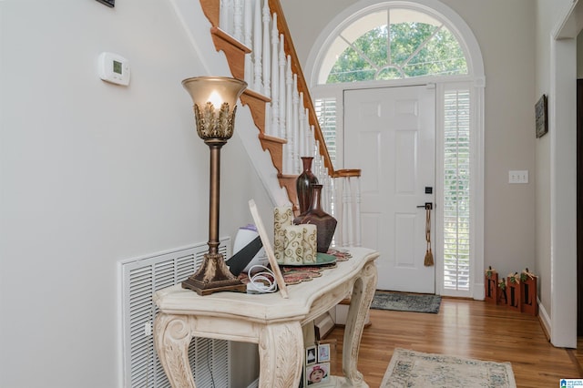 entryway featuring a towering ceiling and light hardwood / wood-style flooring