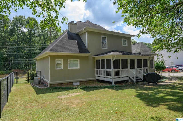 rear view of house with central AC unit and a lawn