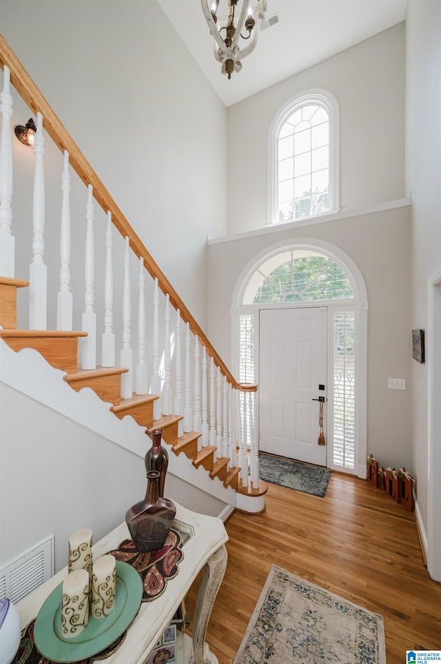 foyer featuring high vaulted ceiling, an inviting chandelier, and wood-type flooring