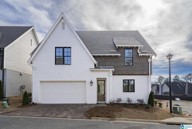 view of front of property featuring driveway, a garage, a shingled roof, fence, and brick siding