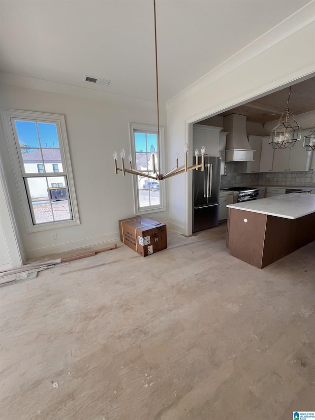 kitchen featuring custom exhaust hood, decorative light fixtures, tasteful backsplash, premium appliances, and a kitchen island