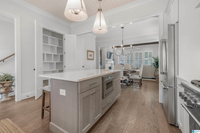 kitchen with white cabinetry, a center island, decorative light fixtures, appliances with stainless steel finishes, and light wood-type flooring