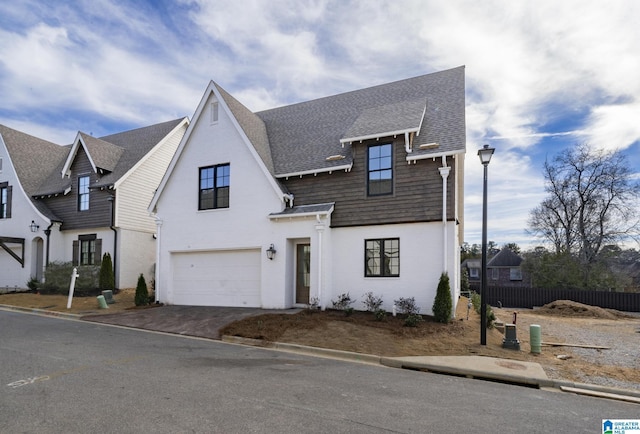 view of front of house with a garage, a shingled roof, driveway, and fence