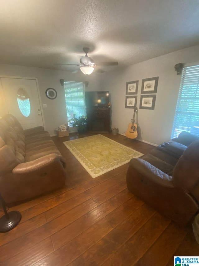 living room with a textured ceiling, wood-type flooring, ceiling fan, and a wealth of natural light