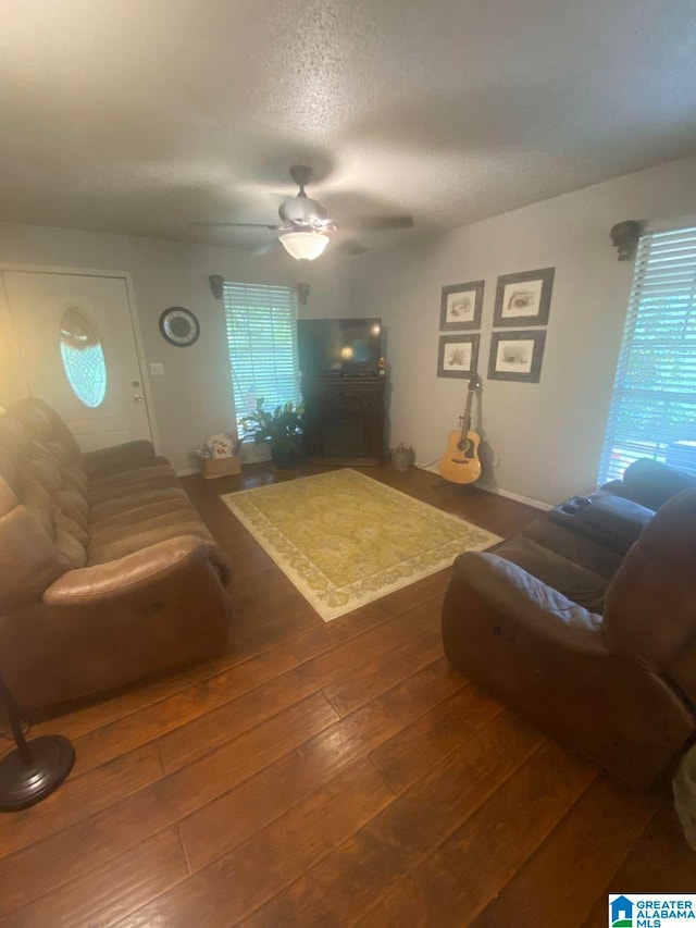 living area featuring wood-type flooring, a ceiling fan, and a textured ceiling