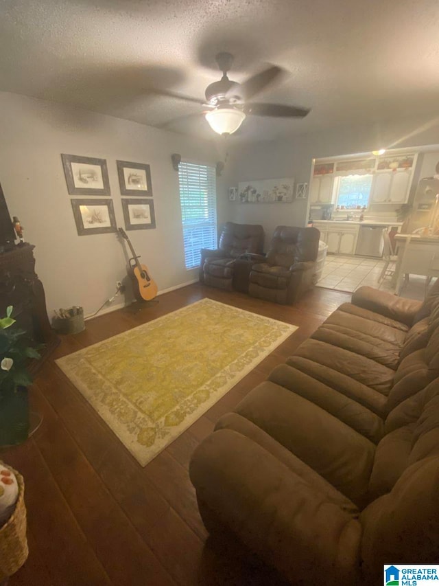 living room with a ceiling fan, a textured ceiling, and wood finished floors
