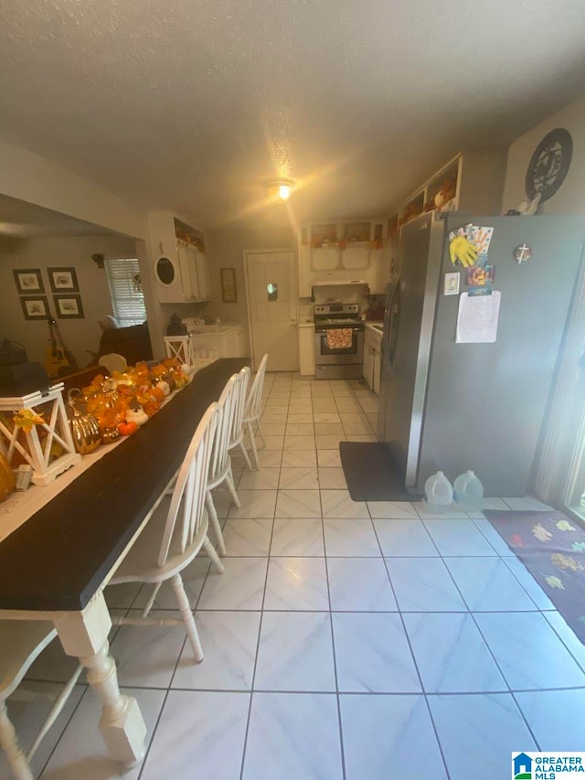 kitchen featuring a textured ceiling, stainless steel appliances, separate washer and dryer, and light tile patterned flooring