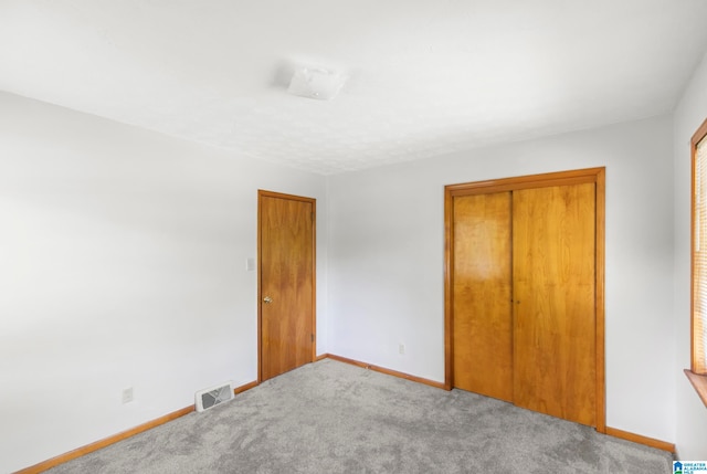 unfurnished bedroom with light carpet and a closet