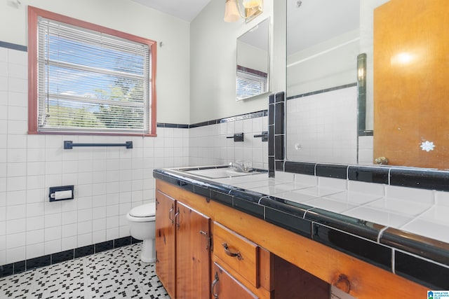 bathroom featuring vanity, toilet, and tile walls