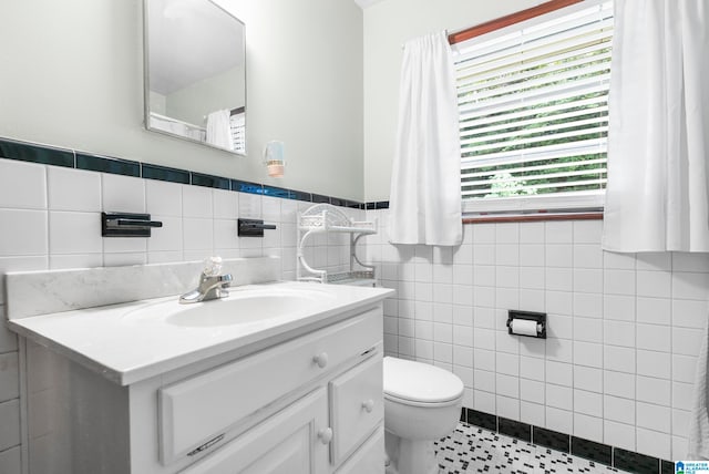 bathroom with vanity, toilet, tile walls, and tile patterned flooring