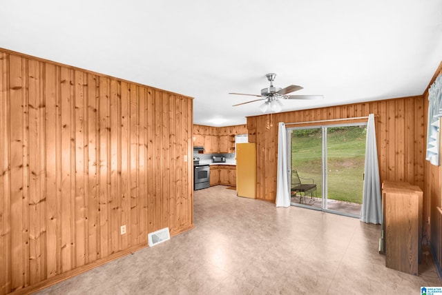 unfurnished living room with ceiling fan and wooden walls