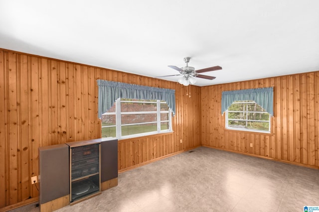 spare room featuring ceiling fan and wooden walls