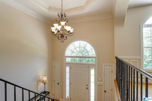 foyer entrance featuring a wealth of natural light, crown molding, an inviting chandelier, and hardwood / wood-style floors