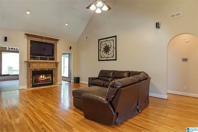 living room with light wood-type flooring, ceiling fan, a wealth of natural light, and a fireplace