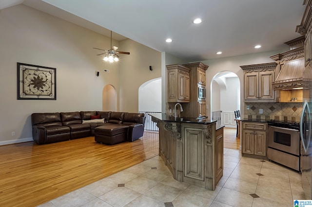 kitchen with backsplash, appliances with stainless steel finishes, light hardwood / wood-style floors, kitchen peninsula, and ceiling fan